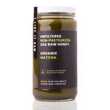 Sauce Bae Matcha Raw Honey on white backdrop with reflection showing side of label. Unfiltered and unpasteurized USA raw honey and organic matcha.