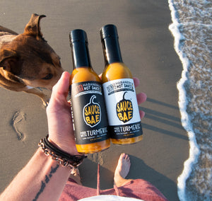 Sauce Bae Skinny Habanero and Hotter Habanero hot sauces being held at the beach