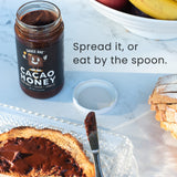 Jar of Sauce Bae Cacao Raw Honey with rich chocolate flavor, shown spread on toasted bread. Healthy chocolate alternative made with raw honey, cacao, and vanilla.