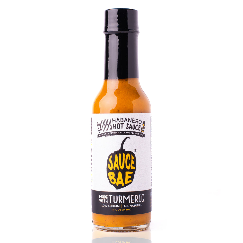 A bottle of Sauce Bae Skinny Habanero Hot Sauce. The label showcases the Sauce Bae logo, emphasizing its ingredients like turmeric and low sodium content.