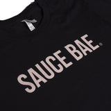 Close up view of Black Sauce Bae t-shirt with off-white text on the chest, water-based print for a soft vintage feel, 100% combed ring-spun cotton.