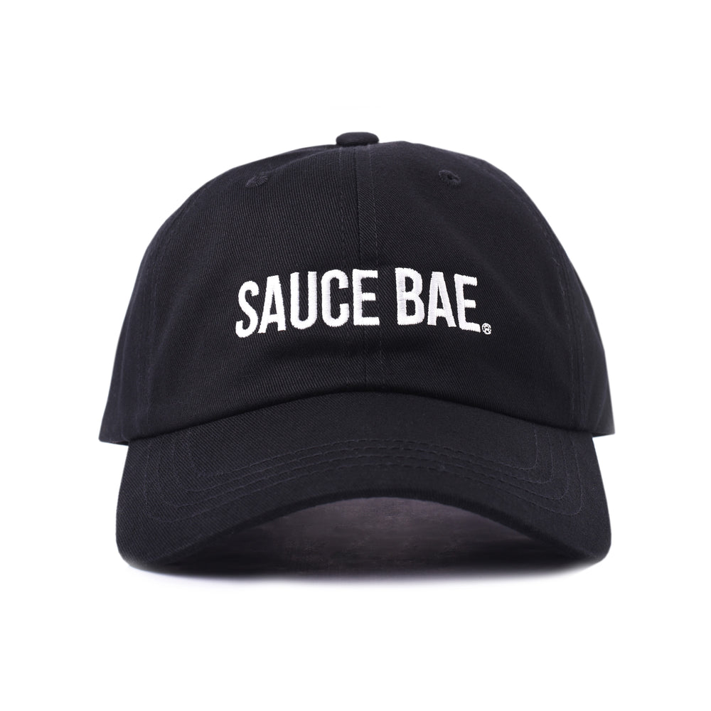 Black dad hat with white embroidered 'Sauce Bae' logo on the front. Perfect for fans of Sauce Bae, a health-focused hot sauce and raw honey brand