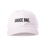White dad hat with white embroidered 'Sauce Bae' logo on the front. Perfect for fans of Sauce Bae, a health-focused hot sauce and raw honey brand