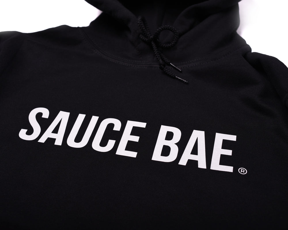 Close up view of front of Sauce Bae Hot Sauce Sweatshirt Hoodie in Black with Sauce Bae Text logo on front,.